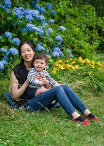 Mother and toddler son sitting on the grass beside blooming hydrangeas, family portrait in Dean Park, Shrewsbury, MA