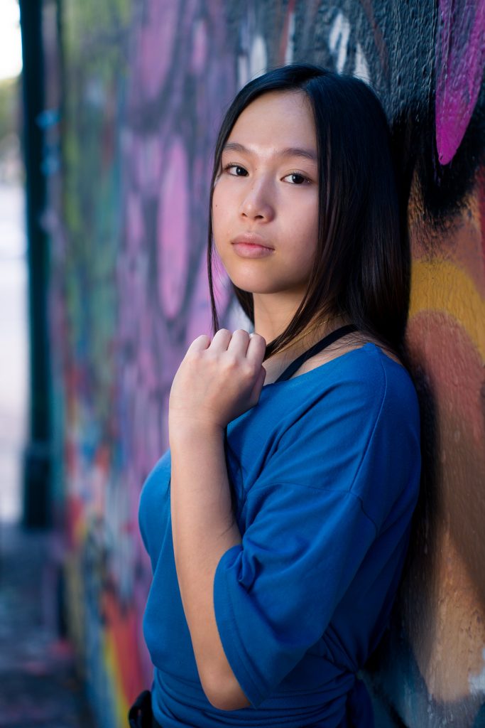 High school girl leaning against a graffiti wall, senior portrait session in Cambridge, MA.