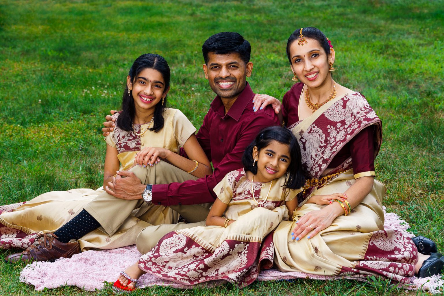 Family of four in matching maroon and cream outfits sitting on a blanket, family portrait at home in Shrewsbury, MA