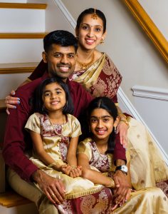 Family of four in traditional Indian attire sitting on a staircase at home, family portrait at a client's home in Northborough, MA