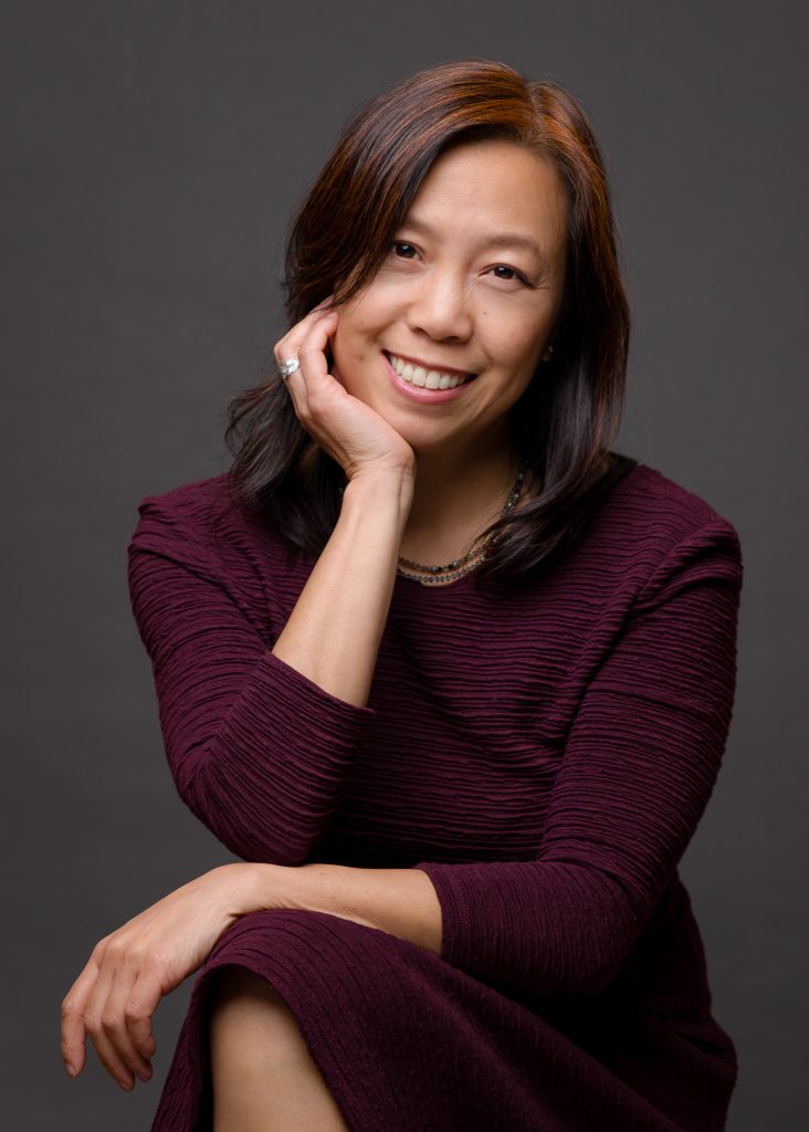 The photographer Emma Fung sitting and smiling at the camera.  