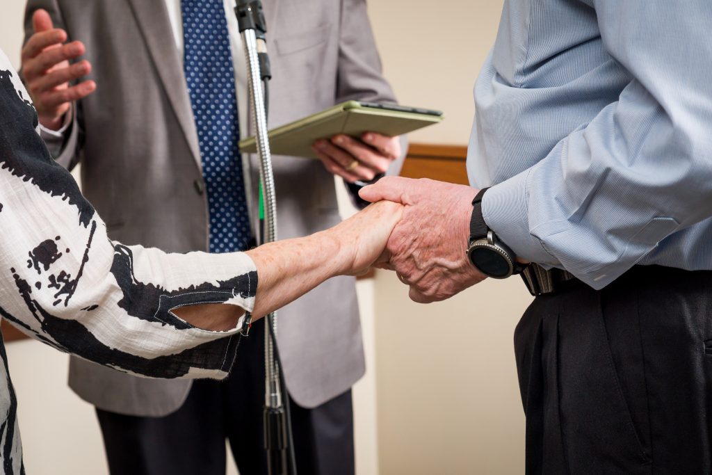 Close-up of a couple holding hands during a wedding vow renewal ceremony, event photography in Boylston, MA