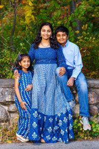 Mother with two children in coordinating blue outfits on a stone wall, family portrait in Dean Park, Shrewsbury, MA