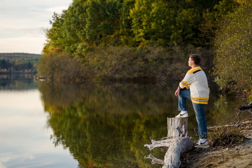High school senior boy looking out at body of water, senior portrait session in West Boylston, MA. 