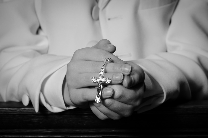 Black-and-white close-up of a child's hands holding a rosary, First Communion photography in St. Catherine of Genoa Church, Somerville, MA
