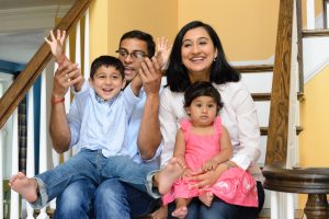 Family of four laughing together on a staircase, family portrait session at a client's home in Shrewsbury, MA